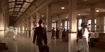 Movie still from “The Last Emperor” (1987), directed by Bernardo Bertolucci – A man in a suit and hat walking through a building; Extreme Wide shot, High angle