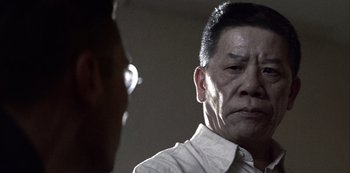 Movie still from “The Last Emperor” (1987), directed by Bernardo Bertolucci – A man in a white shirt is looking at another man in glasses; Close Up shot, Over the shoulder angle
