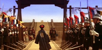Movie still from “The Last Emperor” (1987), directed by Bernardo Bertolucci – A group of people standing on a dirt road; Extreme Wide shot, Low angle