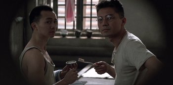 Movie still from “The Last Emperor” (1987), directed by Bernardo Bertolucci – Two asian men sitting at a table with a cup of coffee; Close Up shot, Low angle