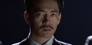 Movie still from “The Last Emperor” (1987), directed by Bernardo Bertolucci – A person wearing a suit and tie; Close Up shot, Low angle