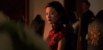 Movie still from “The Last Emperor” (1987), directed by Bernardo Bertolucci – A woman in a red and black dress looking at the camera; Close Up shot, Over the shoulder angle