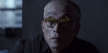 Movie still from “The Last Emperor” (1987), directed by Bernardo Bertolucci – An older man wearing glasses looking at the camera; Close Up shot, Low angle