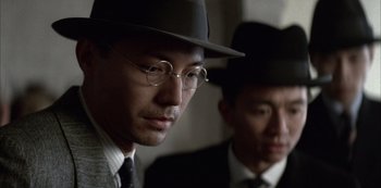 Movie still from “The Last Emperor” (1987), directed by Bernardo Bertolucci – A man in a hat and a suit and a tie; Close Up shot, Over the shoulder angle