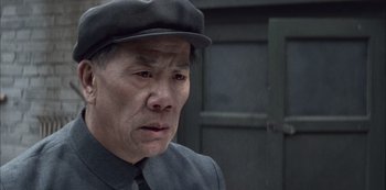 Movie still from “The Last Emperor” (1987), directed by Bernardo Bertolucci – An older man wearing a black hat and a suit; Close Up shot, Low angle