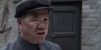 Movie still from “The Last Emperor” (1987), directed by Bernardo Bertolucci – An older man wearing a black hat and a gray suit; Close Up shot, Low angle