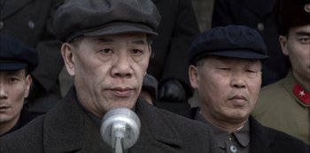 Movie still from “The Last Emperor” (1987), directed by Bernardo Bertolucci – A man in a black hat is speaking into a microphone; Close Up shot, Low angle