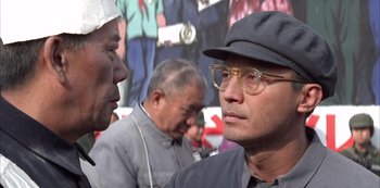 Movie still from “The Last Emperor” (1987), directed by Bernardo Bertolucci – A group of men standing next to each other on a street; Close Up shot, Over the shoulder angle