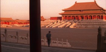 Movie still from “The Last Emperor” (1987), directed by Bernardo Bertolucci – A man standing on the side of a road near a building; Extreme Wide shot, High angle