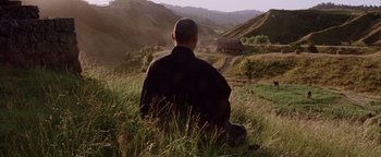 Movie still from “The Last Samurai” (2003), directed by Edward Zwick – A man sitting in the grass looking out at the mountains; Wide shot, Low angle