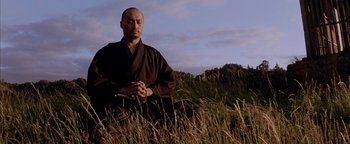 Movie still from “The Last Samurai” (2003), directed by Edward Zwick – A man sitting in the grass with his eyes closed; Medium shot, Low angle