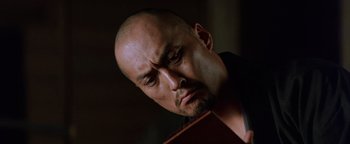 Movie still from “The Last Samurai” (2003), directed by Edward Zwick – A man with a bald head is holding a book; Close Up shot, Low angle