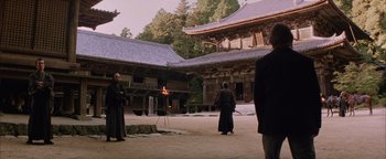 Movie still from “The Last Samurai” (2003), directed by Edward Zwick – A group of people standing in a courtyard with a fire burning; Extreme Wide shot, Low angle