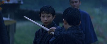 Movie still from “The Last Samurai” (2003), directed by Edward Zwick – Two young boys are practicing martial arts in the rain; Close Up shot, Over the shoulder angle