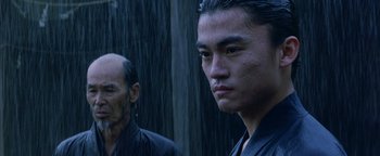 Movie still from “The Last Samurai” (2003), directed by Edward Zwick – Two asian men standing next to each other in the rain; Close Up shot, Low angle