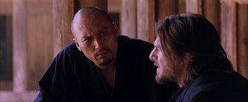 Movie still from “The Last Samurai” (2003), directed by Edward Zwick – A man with a shaved head and a man with long hair; Close Up shot, Over the shoulder angle