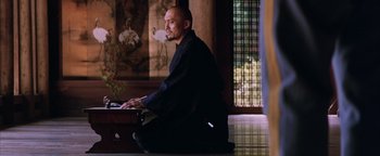 Movie still from “The Last Samurai” (2003), directed by Edward Zwick – A man sitting on the ground in front of a laptop computer; Medium shot, Low angle