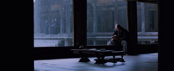 Movie still from “The Last Samurai” (2003), directed by Edward Zwick – A person sitting on a bench in front of a window; Wide shot, High angle