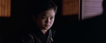 Movie still from “The Last Samurai” (2003), directed by Edward Zwick – A young asian boy wearing a black robe; Close Up shot, Over the shoulder angle