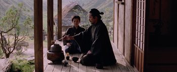 Movie still from “The Last Samurai” (2003), directed by Edward Zwick – A man and a boy sitting on the porch of a house; Medium shot, Over the shoulder angle