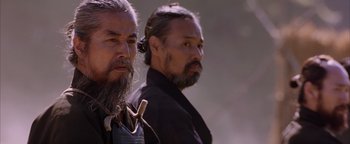 Movie still from “The Last Samurai” (2003), directed by Edward Zwick – Two men standing next to each other in front of trees; Close Up shot, Low angle