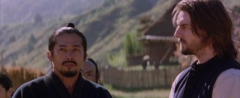 Movie still from “The Last Samurai” (2003), directed by Edward Zwick – A man in a black shirt is standing in front of a house; Close Up shot, Over the shoulder angle