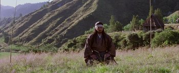 Movie still from “The Last Samurai” (2003), directed by Edward Zwick – A man sitting in the grass in front of a mountain; Wide shot, Low angle