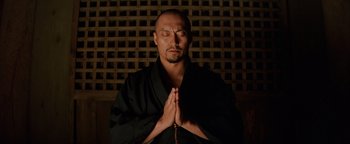 Movie still from “The Last Samurai” (2003), directed by Edward Zwick – A man in a black robe with his hands in prayer position; Close Up shot, Low angle