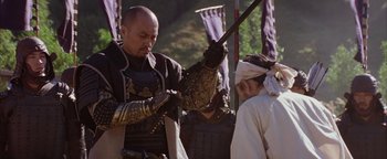Movie still from “The Last Samurai” (2003), directed by Edward Zwick – A man holding a sword while standing next to another man; Medium shot, Over the shoulder angle