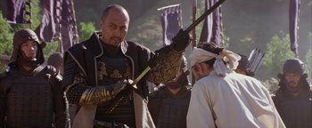 Movie still from “The Last Samurai” (2003), directed by Edward Zwick – A man holding a sword in front of a group of people; Medium shot, Over the shoulder angle