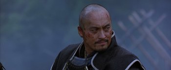 Movie still from “The Last Samurai” (2003), directed by Edward Zwick – A man with a beard and a neck brace on; Close Up shot, Over the shoulder angle