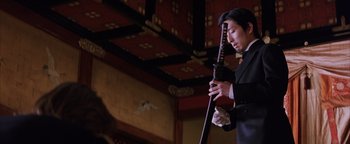 Movie still from “The Last Samurai” (2003), directed by Edward Zwick – A person holding a sword in a room with a red ceiling; Medium shot, Low angle