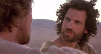 Movie still from “The Last Temptation of Christ” (1988), directed by Martin Scorsese – A man with long hair and a beard looking at another man with curly hair; Close Up shot, Over the shoulder angle