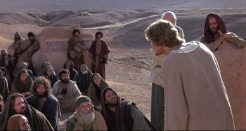 Movie still from “The Last Temptation of Christ” (1988), directed by Martin Scorsese – A group of men in the desert talking to each other; Wide shot, High angle