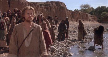 Movie still from “The Last Temptation of Christ” (1988), directed by Martin Scorsese – A group of people walking along a rocky path; Medium shot, Low angle