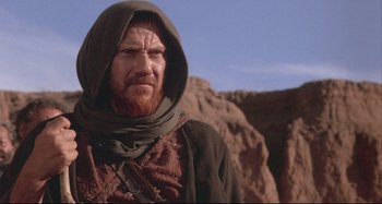 Movie still from “The Last Temptation of Christ” (1988), directed by Martin Scorsese – A man with a beard wearing a hood and a cape; Medium shot, Low angle
