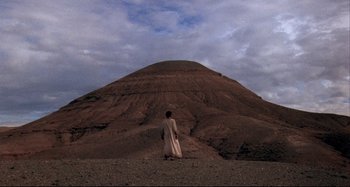 Movie still from “The Last Temptation of Christ” (1988), directed by Martin Scorsese – A man standing in front of a large mountain; Extreme Wide shot, Low angle