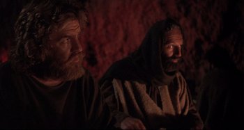 Movie still from “The Last Temptation of Christ” (1988), directed by Martin Scorsese – Two men sitting next to each other in a cave; Medium shot, Low angle