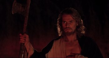Movie still from “The Last Temptation of Christ” (1988), directed by Martin Scorsese – A man with long blonde hair holding a wooden cross; Medium shot, Low angle