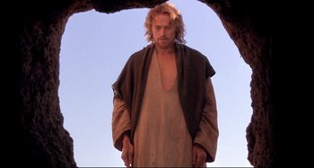 Movie still from “The Last Temptation of Christ” (1988), directed by Martin Scorsese – A man standing in front of a cave looking at the sky; Medium shot, Low angle