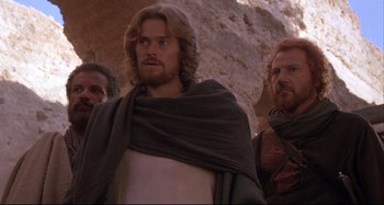 Movie still from “The Last Temptation of Christ” (1988), directed by Martin Scorsese – A group of men standing next to each other in front of a rock wall; Medium shot, Low angle