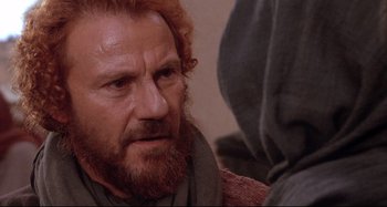 Movie still from “The Last Temptation of Christ” (1988), directed by Martin Scorsese – A man with a beard and a red beard is talking to another man; Close Up shot, Over the shoulder angle