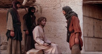 Movie still from “The Last Temptation of Christ” (1988), directed by Martin Scorsese – A group of men standing next to each other near a wall; Medium shot, Over the shoulder angle