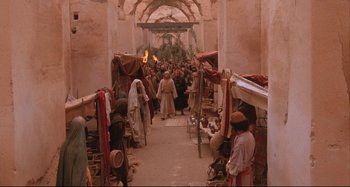 Movie still from “The Last Temptation of Christ” (1988), directed by Martin Scorsese – A group of people walking down a walkway; Extreme Wide shot, High angle