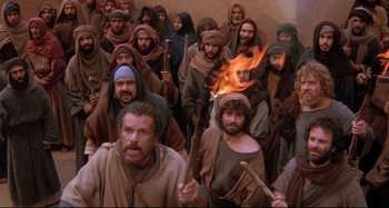 Movie still from “The Last Temptation of Christ” (1988), directed by Martin Scorsese – A group of men standing next to each other in front of a fire; Wide shot, High angle