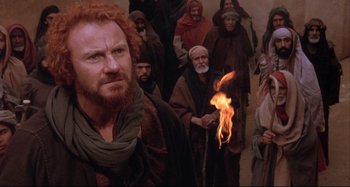 Movie still from “The Last Temptation of Christ” (1988), directed by Martin Scorsese – A group of people in a room with a fire; Medium shot, Over the shoulder angle