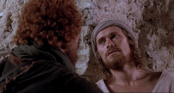 Movie still from “The Last Temptation of Christ” (1988), directed by Martin Scorsese – A man with a beard and a head scarf is looking at another man in the mirror; Close Up shot, Over the shoulder angle