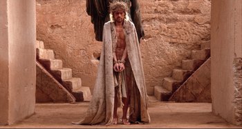 Movie still from “The Last Temptation of Christ” (1988), directed by Martin Scorsese – A man with a crown of thorns on his head; Wide shot, High angle