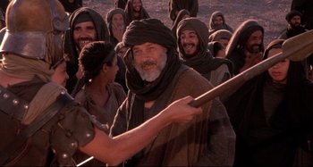 Movie still from “The Last Temptation of Christ” (1988), directed by Martin Scorsese – A group of men in a field with a spear; Medium shot, Over the shoulder angle