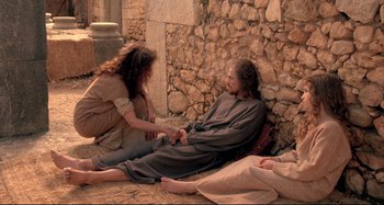 Movie still from “The Last Temptation of Christ” (1988), directed by Martin Scorsese – A woman kneeling down next to a man in a robe; Wide shot, High angle